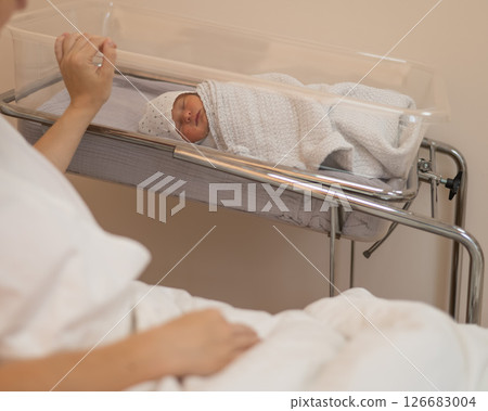A young mother admires her newborn son in the maternity hospital.  126683004