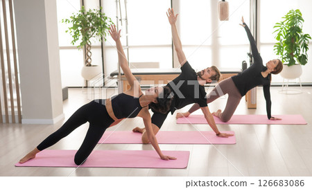 Two women and a man are doing yoga in the studio. 126683086