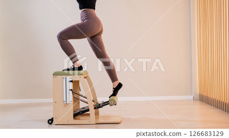 Woman doing pilates classic chair. Woman doing pilates classic chair. 126683129