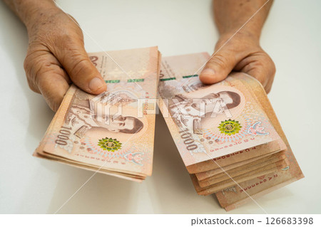 Asian elder senior woman patient holding Thai banknotes money in her hand, Cost of living and medical care. 126683398