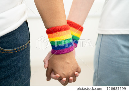 Asian LGBT couple woman holding hand wearing rainbow wristband. 126683399