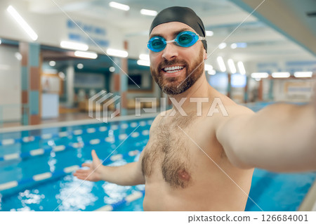 Well-built young man in swimming cap in the pool looking contented 126684001