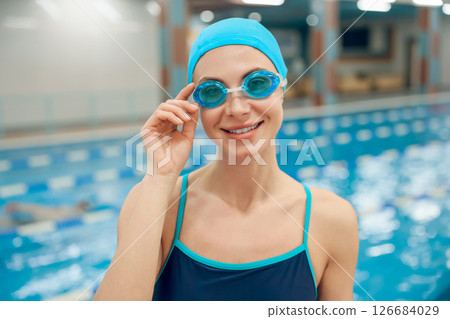 Young woman in swimsuit and swimming cap getting ready to swim in the pool 126684029