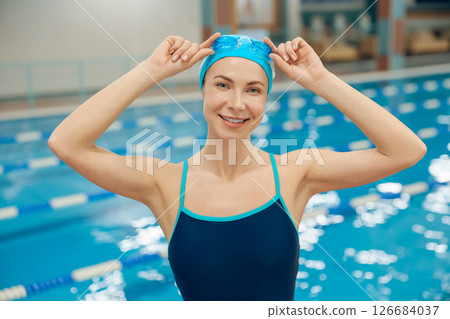 Young woman in swimsuit and swimming cap getting ready to swim in the pool 126684037