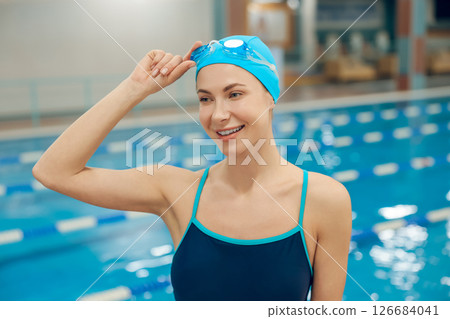 Young woman in swimsuit and swimming cap getting ready to swim in the pool 126684041