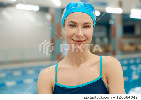 Young woman in swimsuit and swimming cap getting ready to swim in the pool Young woman in swimsuit and swimming cap getting ready to swim in the pool 126684042