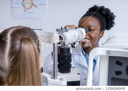 Female ophthalmologist working using optical medical tool while working with patient Female ophthalmologist working using optical medical tool while working with patient 126684049