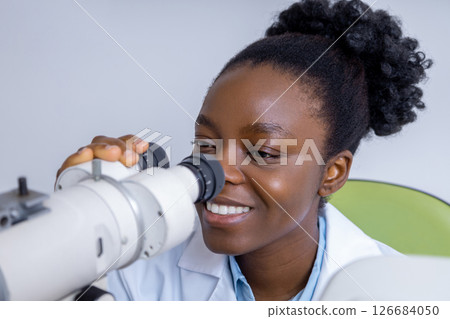 Female ophthalmologist working using optical medical tool while working with patient Female ophthalmologist working using optical medical tool while working with patient 126684050