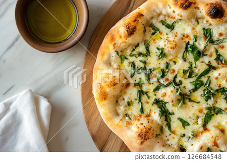 Rustic pizza topped with fresh basil and olive oil on a wooden board with ample space for text 126684548