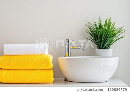 Bright bathroom arrangement with compact sink and neatly folded towels enhancing space 126684779