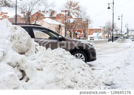 Car against the backdrop of a huge pile of snow, winter cityscape 126685176
