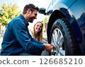 A man helps an unfamiliar woman repair her car on the side of the road 126685210
