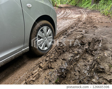 Stock photo of the front tire of a car stuck in mud 126685306