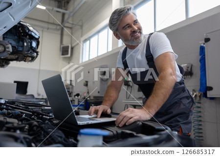Mechanic performing diagnostics with laptop 126685317