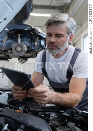 Mechanic performing diagnostics with tablet Mechanic performing diagnostics with tablet 126685337