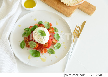 Fresh Caprese salad with mozzarella, tomatoes, and basil, served with bread. Fresh Caprese salad with mozzarella, tomatoes, and basil, served with bread. 126685869