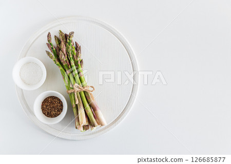 Fresh asparagus shoots with spices on white table. Top view Fresh asparagus shoots with spices on white table. Top view 126685877