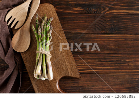 Asparagus tied bundle and wooden utensils on rustic table. Top view Asparagus tied bundle and wooden utensils on rustic table. Top view 126685882
