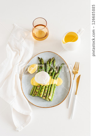 Poached egg with grilled asparagus and hollandaise sauce on white table. Top view 126685885
