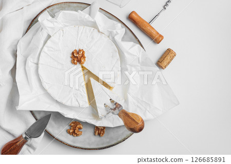 Cutted fresh brie cheese with walnuts on white table. Top view Cutted fresh brie cheese with walnuts on white table. Top view 126685891