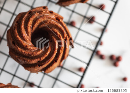 Mini chocolate bundt cakes on a cooling rack. Top view Mini chocolate bundt cakes on a cooling rack. Top view 126685895