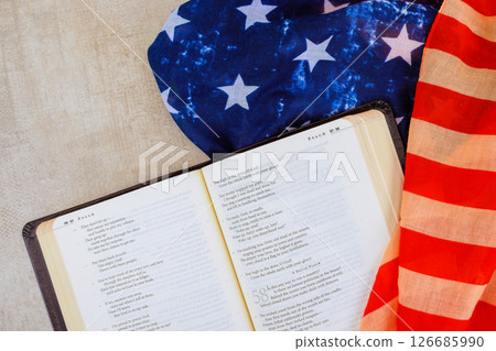 24 April 2025 Washington DC US Bible open book displays poetic verses on textured surface, American flag fabrics of national pride. 126685990
