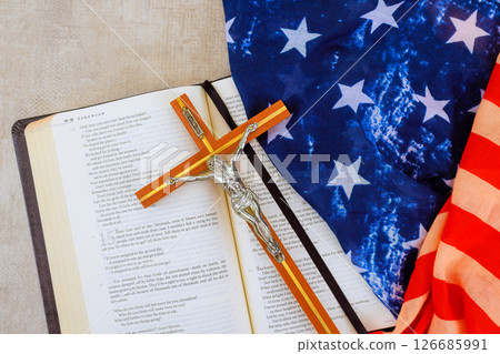 24 April 2025 Washington DC US Bible open to passage sits next to crucifix, folded American flag, representing faith, patriotism 24 April 2025 Washington DC US Bible open to passage sits next to crucifix, folded American flag, representing faith, patriotism 126685991