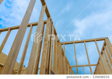 Wooden framework being assembled wall is beams in construction site with during works day 126686010