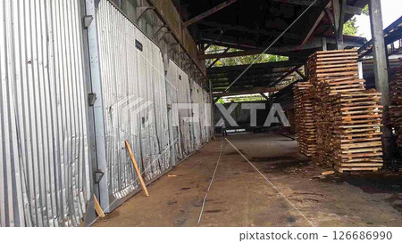 plywood processing plant showcasing Industrial Warehouse Interior with Stacks of Materials and Machinery, warehouse featuring industrial equipment, materials, and wooden pallets 126686990