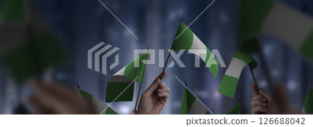 Nigeria flags in their hands on a blurred urban background 126688042