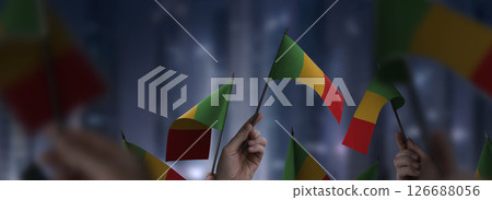 Mali flags in their hands on a blurred urban background 126688056