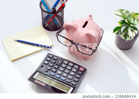 Smart piggy bank wearing glasses, using calculator Smart piggy bank wearing glasses, using calculator 126688414