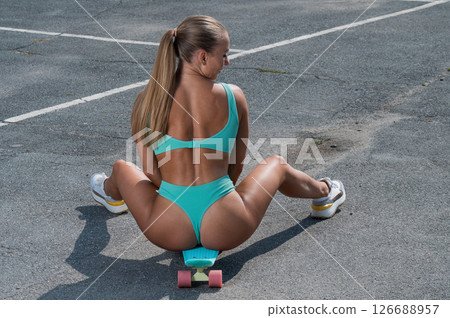 Caucasian woman in a swimsuit with a penny board. Caucasian woman in a swimsuit with a penny board. 126688957