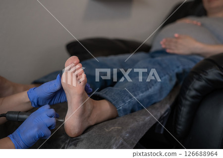 Pregnant woman on a hardware pedicure procedure in a beauty salon.  126688964