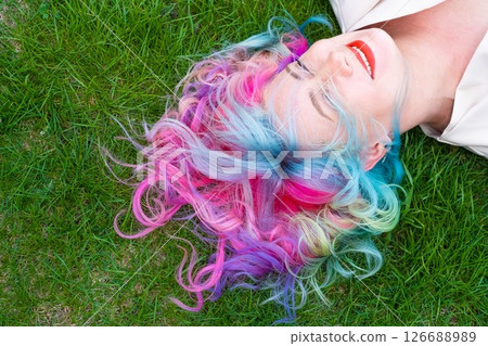 Caucasian woman with colorful hair on green grass. 126688989