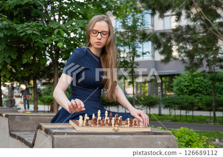 Caucasian woman playing chess outdoors. Caucasian woman playing chess outdoors. 126689112