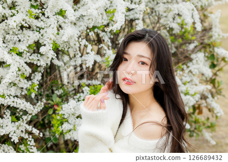 A young woman in white clothes relaxes around snow willow flowers 126689432