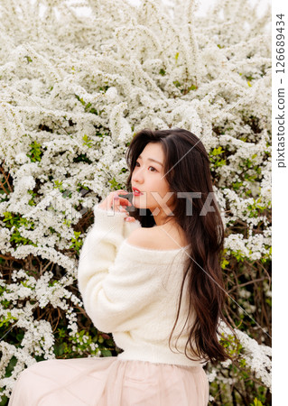 A young woman in white clothes relaxes around snow willow flowers 126689434