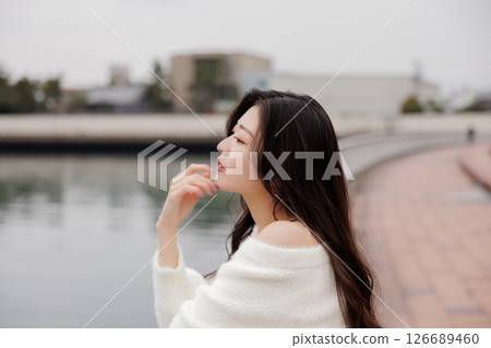 一位身穿白衣的年輕女子在港口休息 126689460