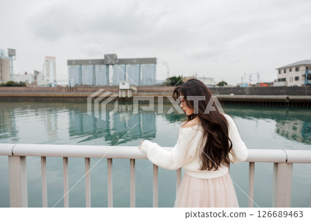 A young woman in white clothes relaxes at the harbor 126689463