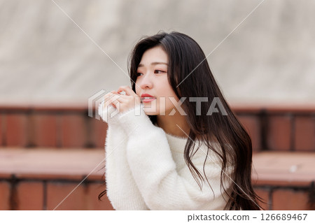 一位身穿白衣的年輕女子在港口休息 126689467