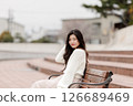 一位身穿白衣的年輕女子在港口休息 126689469