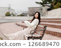 一位身穿白衣的年輕女子在港口休息 126689470