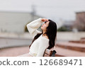 一位身穿白衣的年輕女子在港口休息 126689471