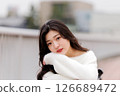 一位身穿白衣的年輕女子在港口休息 126689472