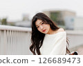 一位身穿白衣的年輕女子在港口休息 126689473