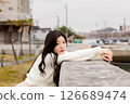 一位身穿白衣的年輕女子在港口休息 126689474