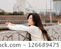 一位身穿白衣的年輕女子在港口休息 126689475