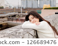 一位身穿白衣的年輕女子在港口休息 126689476