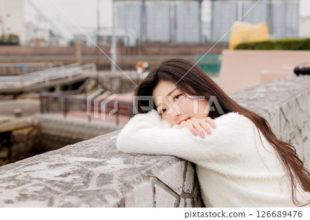 一位身穿白衣的年輕女子在港口休息 126689476